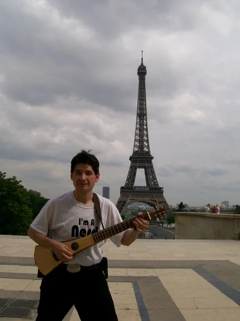 Herbert Midgley playing guitar near the Eiffel Tower